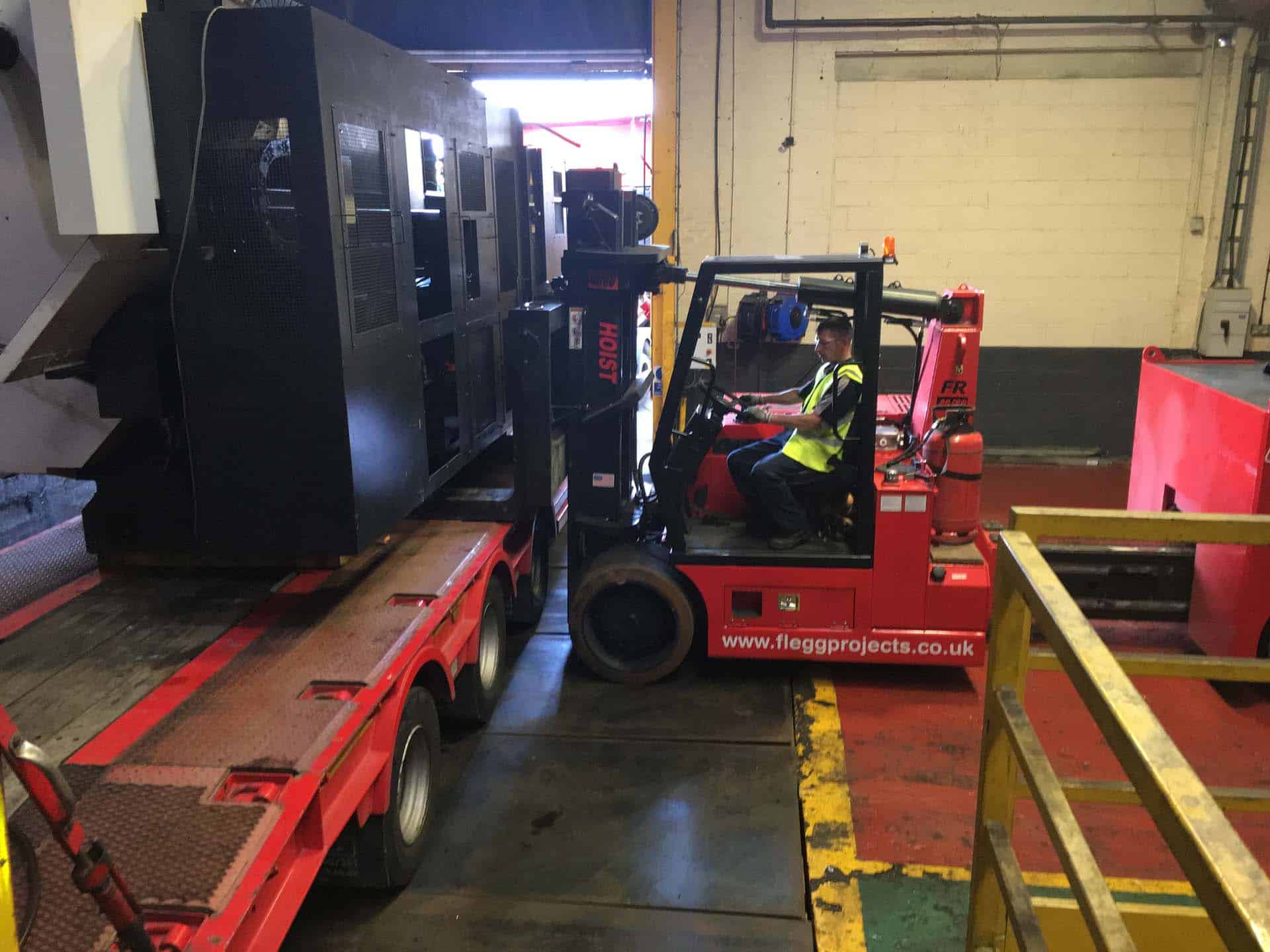 forklift loading a truck with machinery