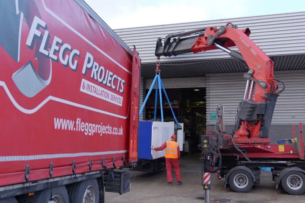 machinery being lifted by a red crane into a truck