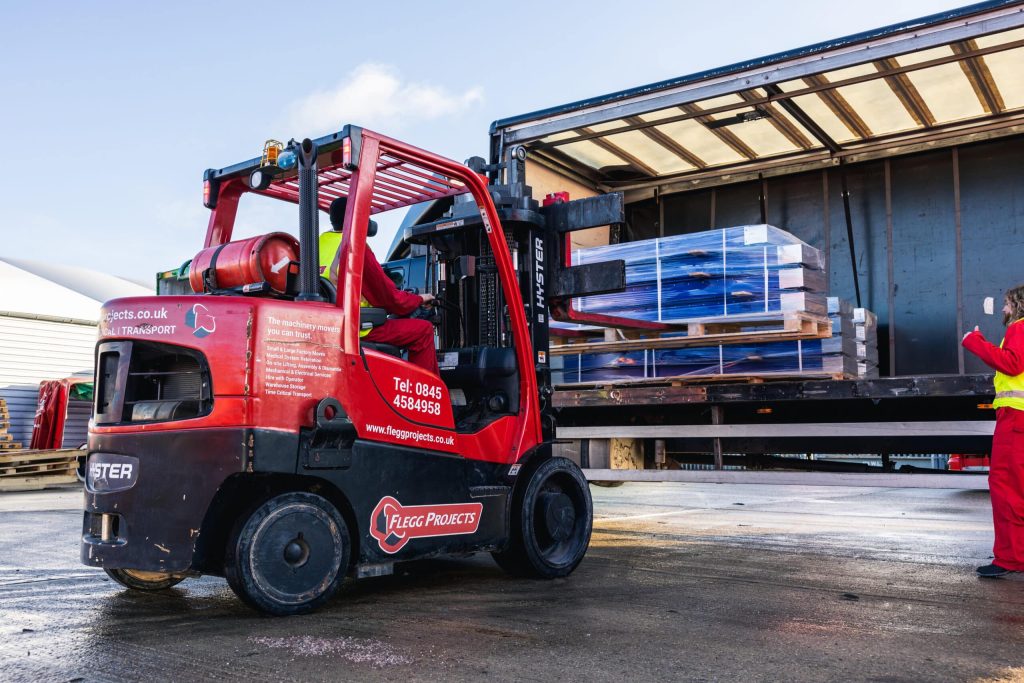 red forklift taking load out of truckbed