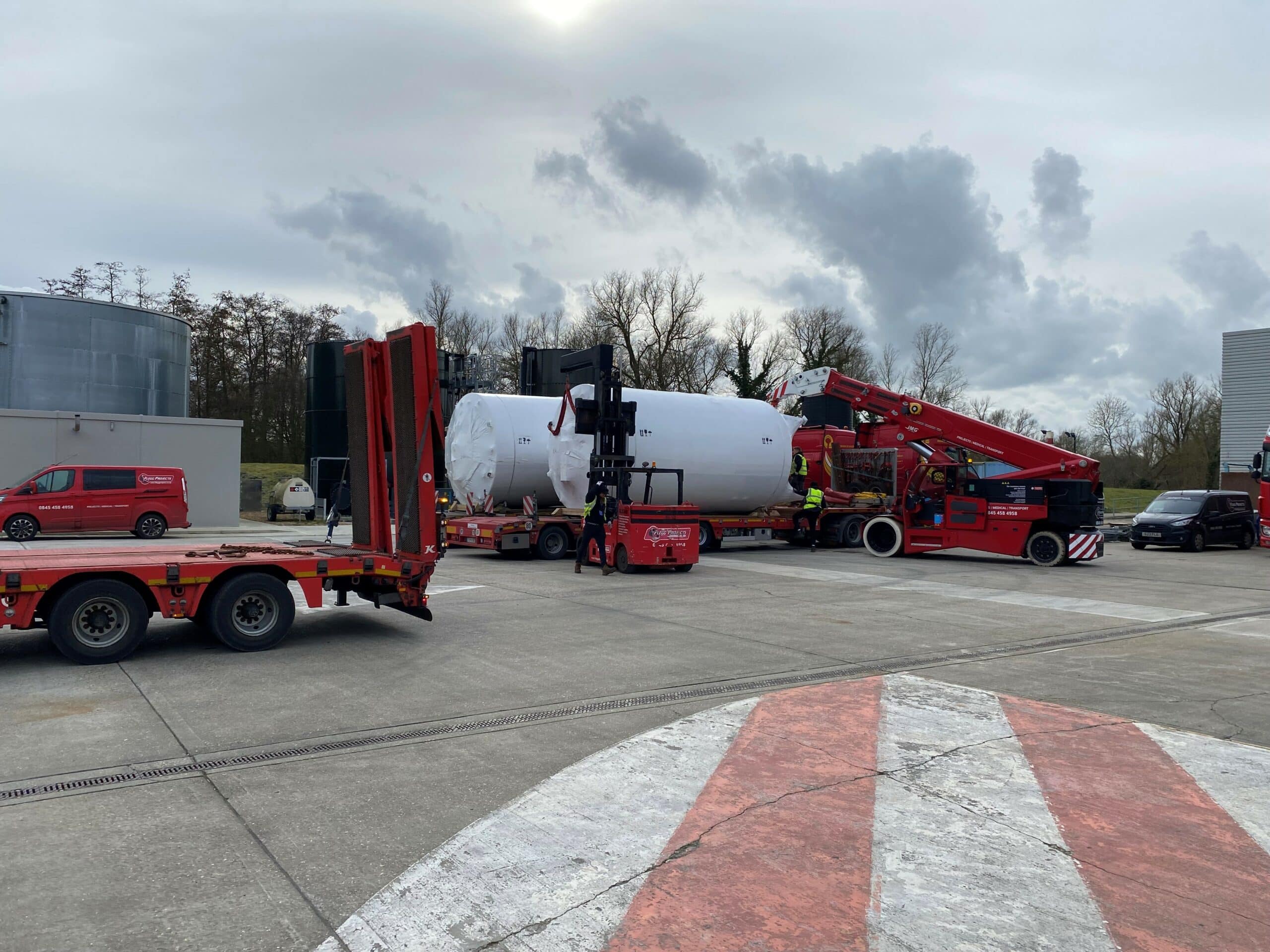 various logistics vehicles parked around large white holding tanks
