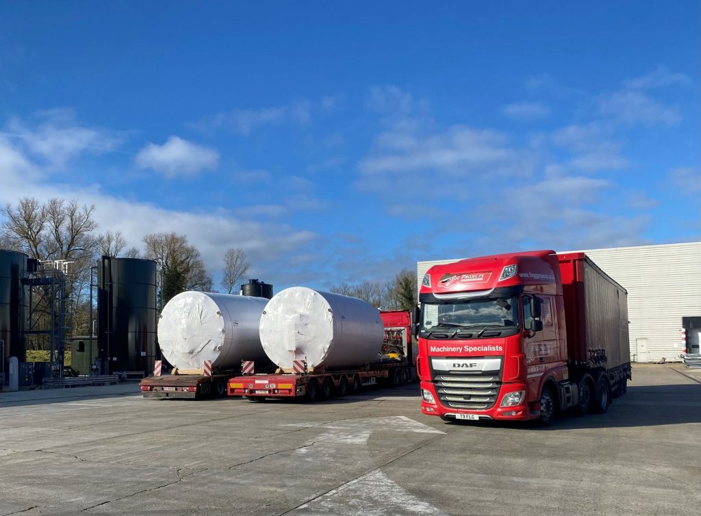 red truck parked next to large silver holding tanks