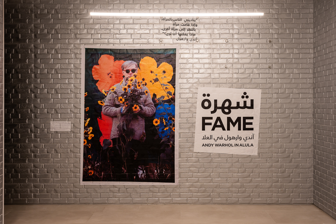 Andy Warhol in AlUla exhibition poster on gallery wall
